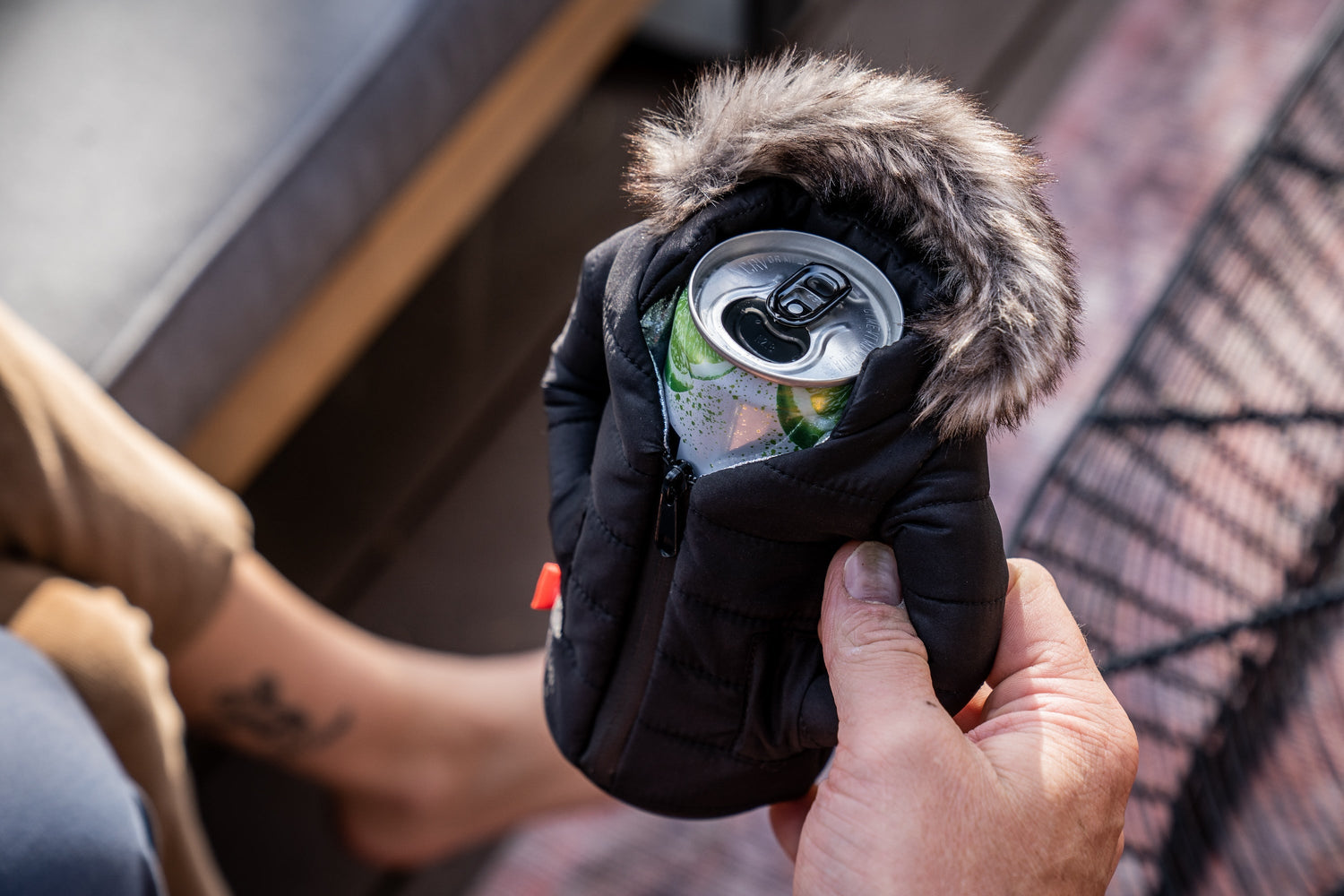 Black Pahka koozie in hand, showing the fur lined hood